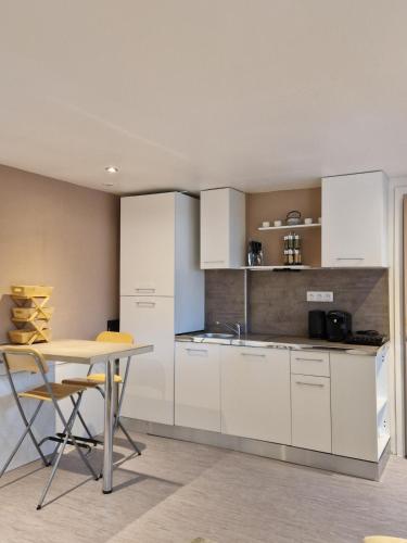 une cuisine avec des armoires blanches et une table avec des chaises dans l'établissement Studio Atypique Jacuzzi, à Tarbes