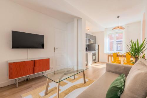 a living room with a couch and a tv on a wall at T2 confortable et bien équipé proche métro in Lambersart