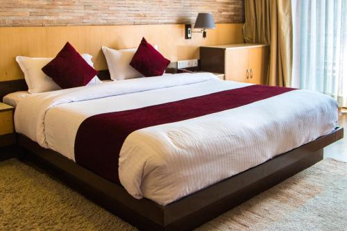 a bedroom with a large bed with red pillows at Hotel Queens Park in Pokhara