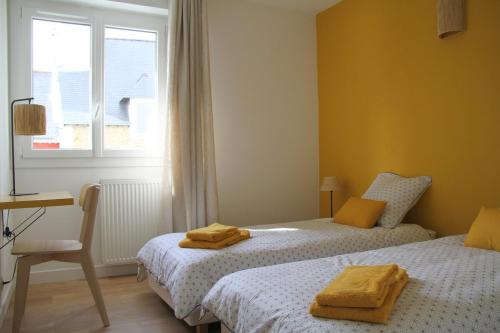 une chambre avec deux lits et un bureau et une fenêtre dans l'établissement Saint-Patern - centre-ville - Wifi, à Vannes