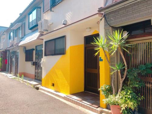 a yellow and white building with palm trees on a street at RInnオリジナル天下茶屋 松 in Osaka