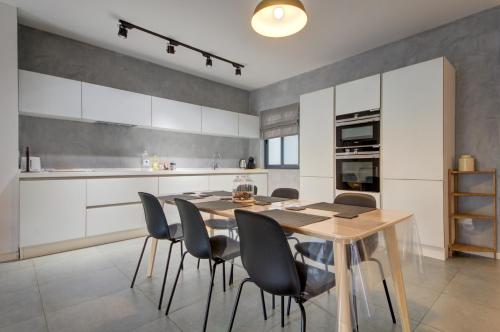 a kitchen with a wooden table and chairs at Modern Marsaxlokk Apartment in Marsaxlokk