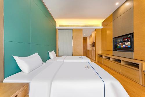 a bedroom with a large white bed and a flat screen tv at eStay Residence·Poly World Trade Center Guangzhou in Guangzhou