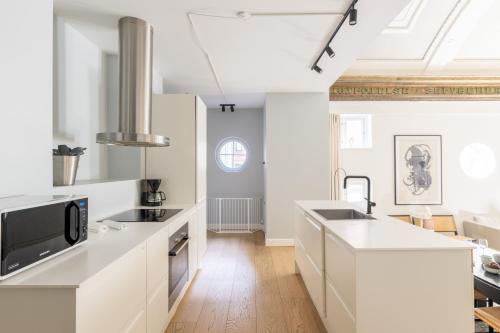 a kitchen with white cabinets and a black microwave at Unique 3 Bedroom Apartment in Vibrant Frederiksberg in Copenhagen