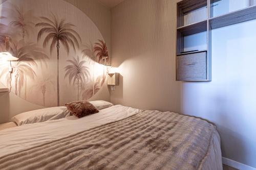 - une chambre avec un grand lit et du papier peint en palmier dans l'établissement Le Yucca - Vue mer 100 m de la plage, à Pietrosella