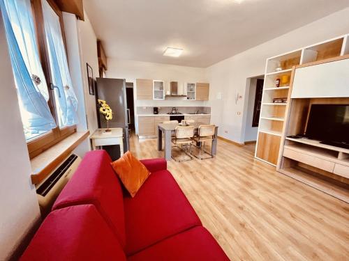 a living room with a red couch and a kitchen at Residenza Bouganville in Torri del Benaco
