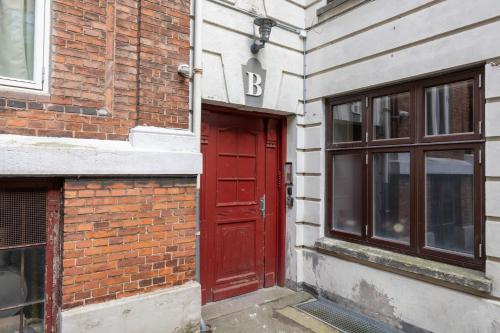 a red door on the side of a brick building at Unique 3 Bedroom Apartment in Vibrant Frederiksberg in Copenhagen