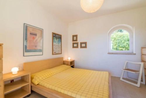 a bedroom with a yellow bed and a window at Villa Stefania - Porto Rafael in Porto Rafael