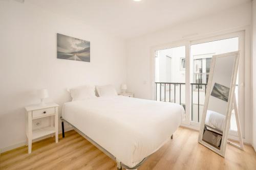a white bedroom with a large white bed and a window at GuestReady - Sunny Sesimbra Escape in Sesimbra