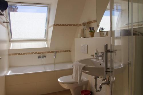 Un baño con lavabo, inodoro y bañera. en Inselblume 27 - Modernes Ferienhaus mit Garten in Burg, en Burg auf Fehmarn