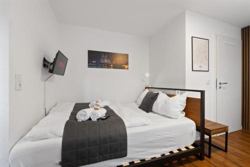 a white bedroom with a bed with towels on it at Modernes Apartement am Rhein in ruhiger Lage in Cologne