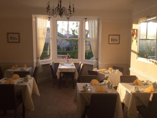 a restaurant with white tables and chairs and windows at The Chatsworth in Weymouth