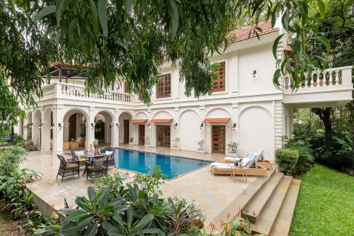 a large white house with a swimming pool at LohonoStays Villa Brisa in Anjuna