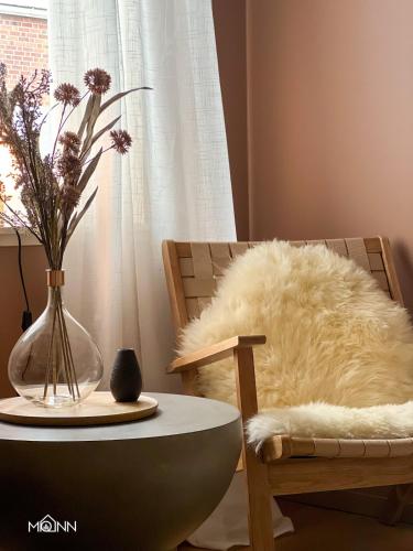 a chair and a table with a white furry pillow and a vase at Piteå Relax and Play Billiard Ap1 in Piteå