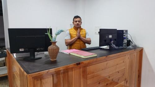 a man standing in front of a desk with a computer at Twin Garden in Gangtok