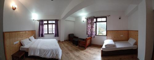 a bedroom with two beds and a couch and two windows at Twin Garden in Gangtok
