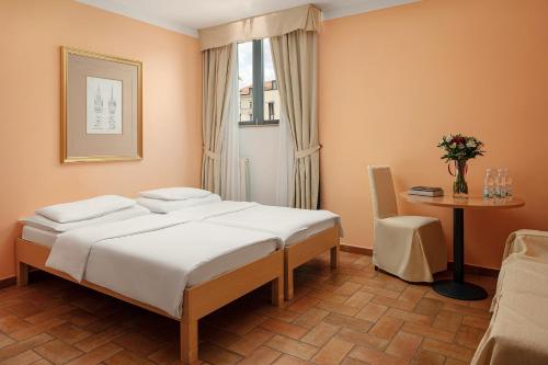a bedroom with a bed and a table and a window at Hotel Roma Prague in Prague