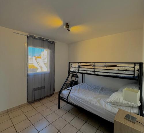 une chambre avec deux lits superposés et une fenêtre dans l'établissement Appartement 7 personnes face mer 7BLION37, au Barcarès