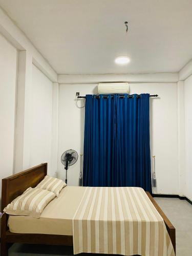 a bedroom with a bed with a blue curtain at Lago Inn in Tissamaharama