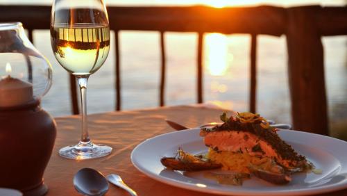 a plate of food and a glass of wine on a table at The David Livingstone Safari Lodge & Spa in Livingstone