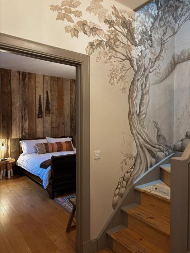 a bedroom with a tree mural on the wall at Jacobite Lodge by The House of Danu in Kingussie