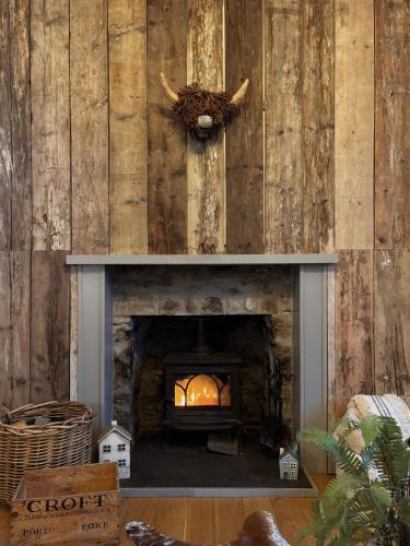 a fireplace in a room with a wall with wood at Jacobite Lodge by The House of Danu in Kingussie
