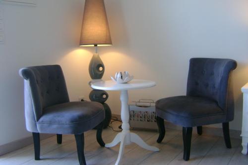 two chairs and a table with a lamp in a room at Gîte & Chambres d'Hôtes - Le Petit Bali in Saint-Pandelon
