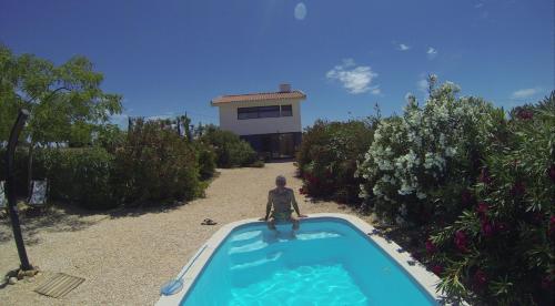 a man sitting on the edge of a swimming pool at Trendy casa de Ferias in Monte da Pedra Alva