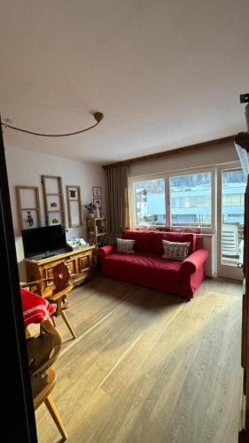 Una sala de estar con un sofá rojo y una gran ventana. en La Sibilla, en Riscone