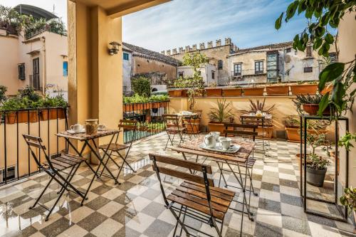 un patio avec tables et chaises sur un balcon dans l'établissement Le Stanze al Genio di Darlon, à Palerme