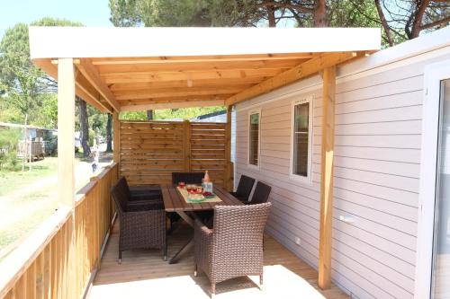 a pergola on a deck with a table and chairs at Happy Camp Mobile Homes in Valamar Camping Lanterna in Poreč