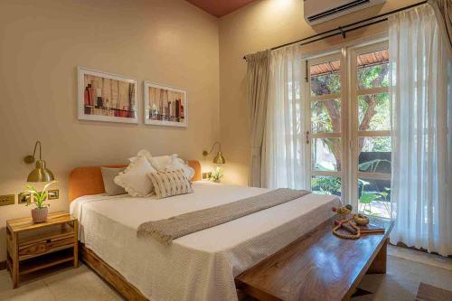 a bedroom with a large bed and a large window at LohonoStays Villa Kefi in Assagao