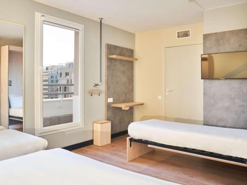 a small room with two beds and a window at ibis budget Issy Les Moulineaux Paris Ouest in Issy-les-Moulineaux