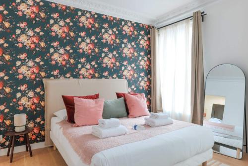 - une chambre avec un grand lit et du papier peint floral dans l'établissement Proche Nation - Appartement à Paris 20e - Haystia, à Paris