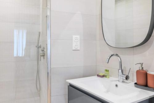 une salle de bain avec un lavabo et une douche avec un miroir dans l'établissement Proche Nation - Appartement à Paris 20e - Haystia, à Paris
