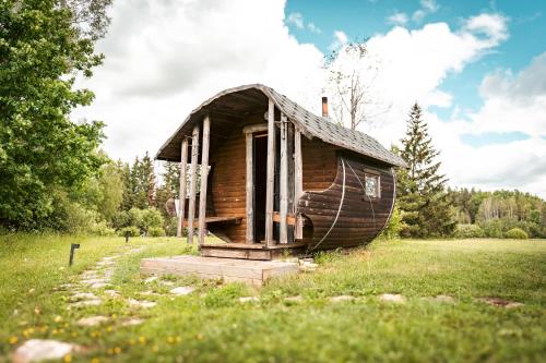 a small wooden house sitting in a field at Saarelux Riverise Villa in Mõraste