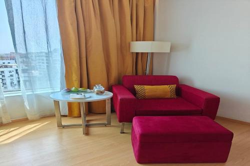 a living room with a red chair and a table at Mercure Hyderabad KCP Banjara Hills, An Accor Hotel in Hyderabad