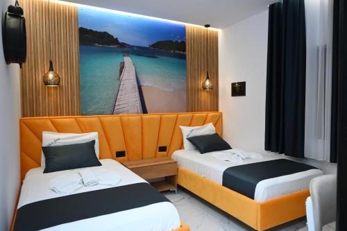 two beds in a room with a picture of a pier at Vila La Familia in Ksamil