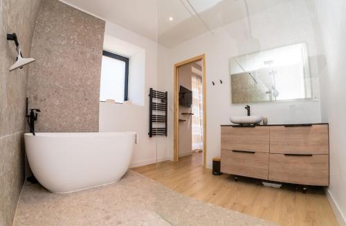 La salle de bains est pourvue d'une grande baignoire blanche et d'un lavabo. dans l'établissement Le mas de Egines, à Saint-Rome-de-Cernon