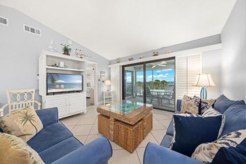 a living room with blue couches and a tv at Sandpiper Beach #405 in Sanibel