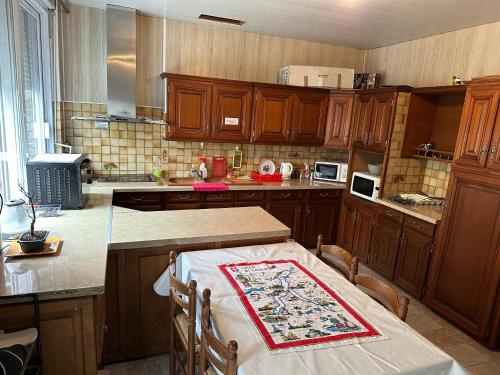 une cuisine avec des placards en bois et une table avec une table sidx sidx sidx dans l'établissement 4 chambres privées dans un pavillon chaleureux, à La Courneuve