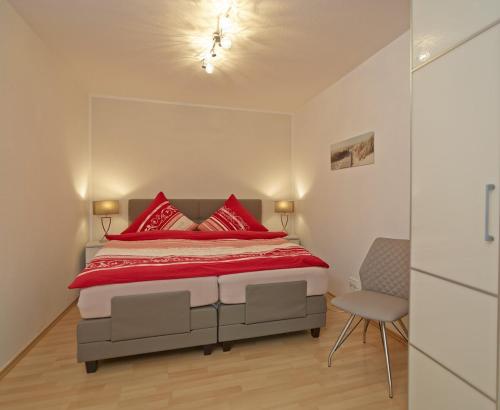 ein Schlafzimmer mit einem Bett mit roten Kissen und einem Stuhl in der Unterkunft Ferienwohnung in Otterndorf in Otterndorf