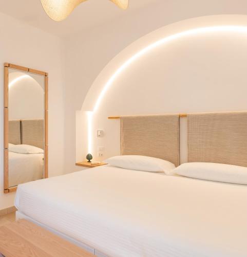 a white bedroom with a large bed and a mirror at Ostuni a Mare in Ostuni