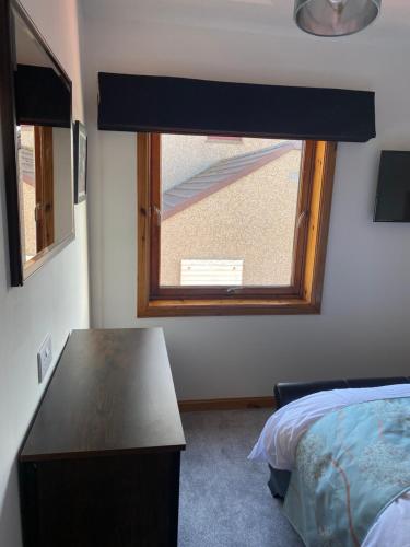 a bedroom with a window and a table and a bed at Apartment 1, Craigmore in Lerwick