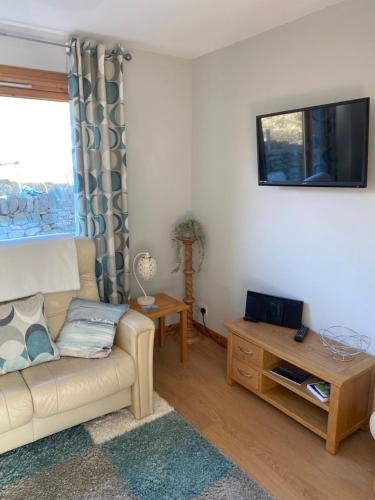 a living room with a couch and a tv at Apartment 1, Craigmore in Lerwick