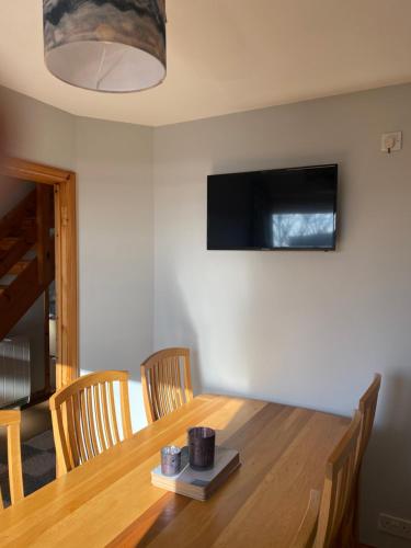 a dining room table with a television on the wall at Apartment 1, Craigmore in Lerwick