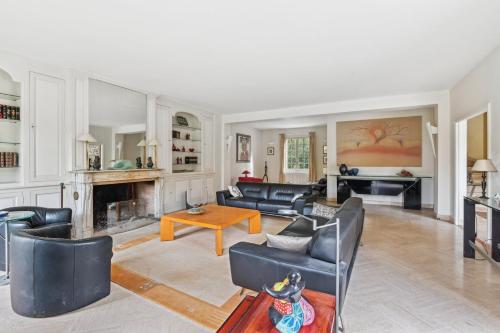 Elle comprend un salon doté d'un mobilier en cuir noir et d'une cheminée. dans l'établissement La Maison des Rois, à Rueil-Malmaison