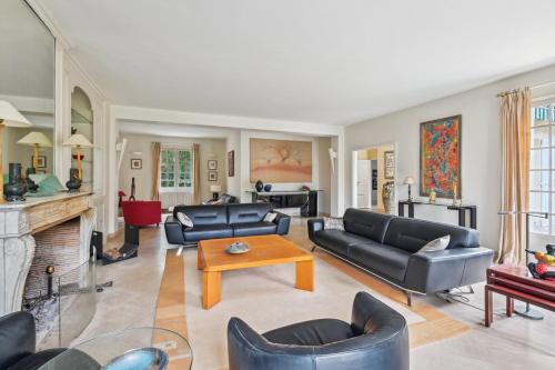 Elle comprend un salon doté d'un mobilier en cuir noir et d'une cheminée. dans l'établissement La Maison des Rois, à Rueil-Malmaison