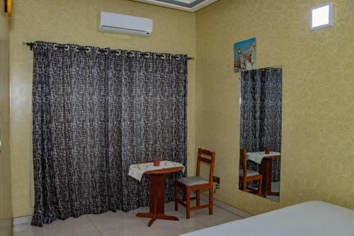 a room with a bed and a table and curtains at ODG Cotonou - Résidences Océan De Grâce in Cotonou