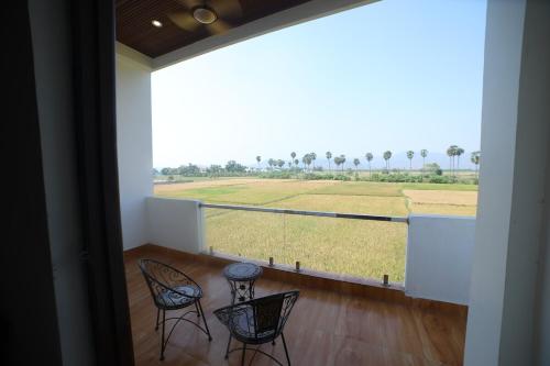 a balcony with two chairs and a large window with a field at Suhana Aangan Homestay in Tirupati